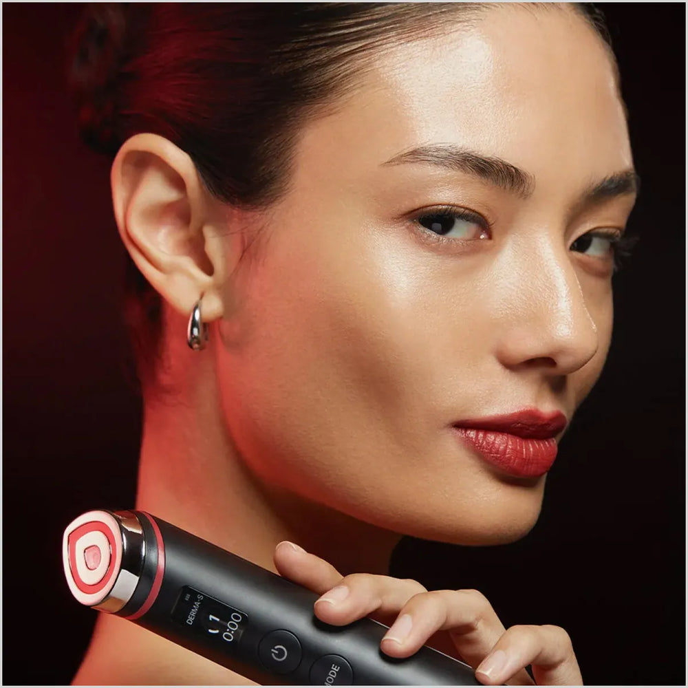 Woman holding a black and red electronic device against a dark background