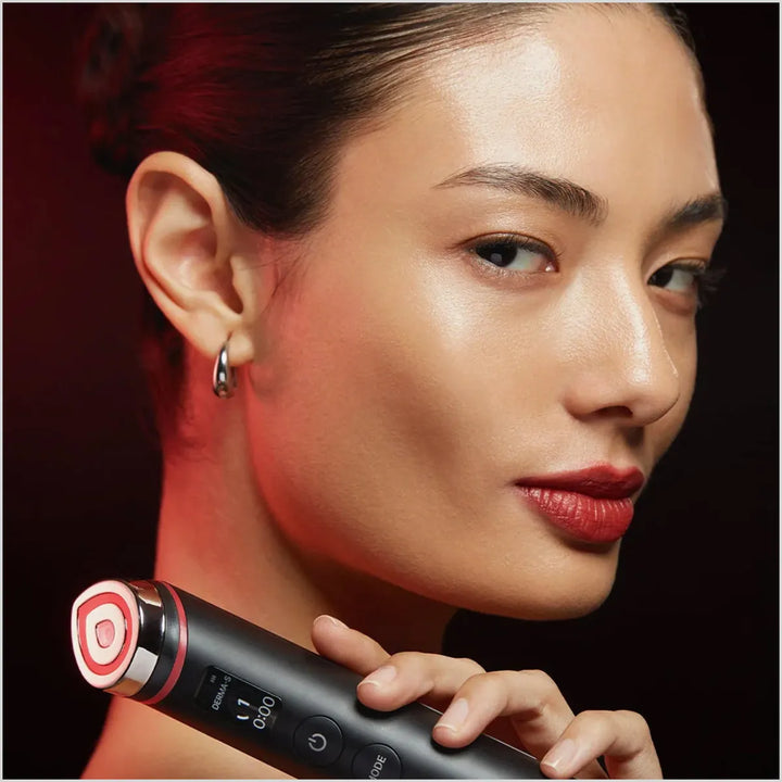 Woman holding a black and red electronic device against a dark background
